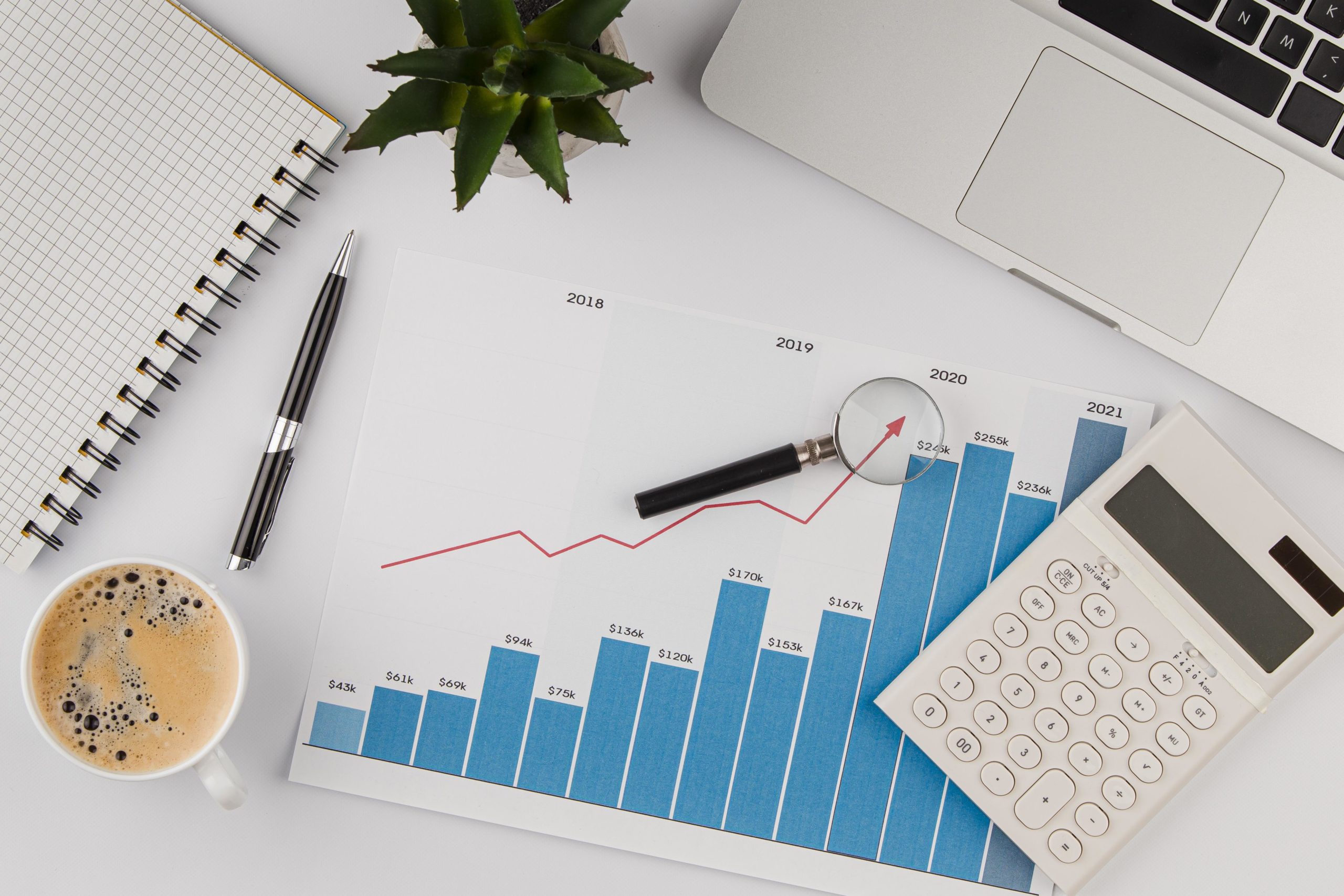 Top View Of Office Desk With Growth Chart And Calculator - Nuvecon